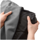 Eine Person, die einen grauen Bezug für ein Haustierbett hält, teilweise geöffnet, um ein schwarzes Innenfutter zu zeigen, das das abnehmbare Design präsentiert.