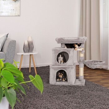 Zwei verspielte Katzen sind in einem grauen Katzenbaum mit mehreren Ebenen und Verstecken zu sehen, der in einem gemütlichen Wohnzimmer steht.