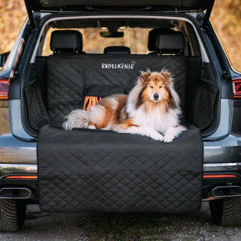 Ein Hund, der auf einem schwarzen gesteppte Haustier-Sitzbezug im Kofferraum eines SUVs ruht, mit dem sichtbaren Text "Rudel König" auf dem Bezug.