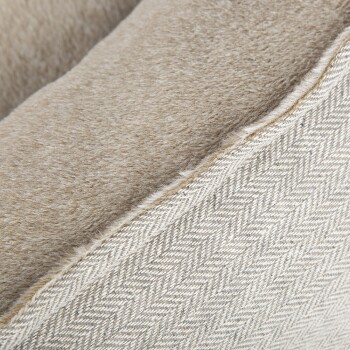 Nahaufnahme eines weichen, beigen Haustierbettes mit einer plüschigen Oberseite und einer strukturierten Fischgrätmuster-Seite.
