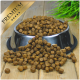 Eine Edelstahl-Haustierfutterschüssel, die über kleine, braune Kroketten überläuft, beschriftet mit "PREMIUM" in einem goldenen Banner oben.