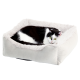 Eine schwarz-weiße Katze, die in einem plüschigen, quadratischen Haustierbett mit einem weichen, flauschigen Rand entspannt, vor einem weißen Hintergrund.