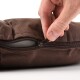 Eine Nahaufnahme einer Hand, die ein braunes Haustierbett aufzippt, das den strukturierten Stoff und das Reißverschlussdetail zeigt.