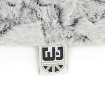Eine Nahaufnahme einer weichen, grauen Haustierdecke mit einem Etikett mit dem Logo "W&J" und einem Union Jack-Design.