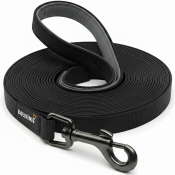 Schwarze Haustierleine, ordentlich aufgerollt, mit einem stabilen Clip und einem Etikett mit dem Text 'RUDELKÖNIG' in Weiß und Orange.