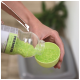 A person pours bright green pet litter beads from a clear bottle labeled "Premiere" into a small green bowl.