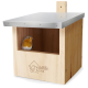 Ein Holzvogelhaus mit einem Metalldach, mit einem kleinen orange-grauen Vogel, der herausblickt, graviert mit "Wildtierheim."
