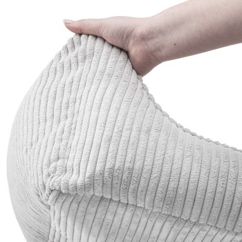 Eine Hand drückt sanft auf ein weiches, strukturiertes, hellgraues Haustierbett mit vertikalen Rippungen, das sein plüschiges Material zeigt.