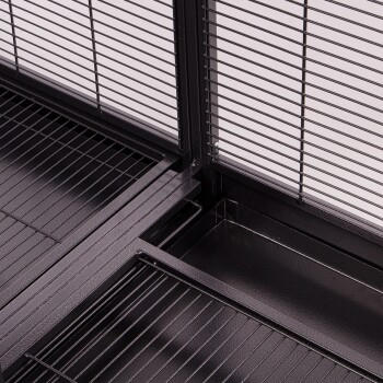 Nahaufnahme des Innenraums eines schwarzen Metallhaustierkäfigs mit horizontalen Stangen, einer herausnehmbaren Schublade und Drahtregalen für den Komfort des Haustiers.