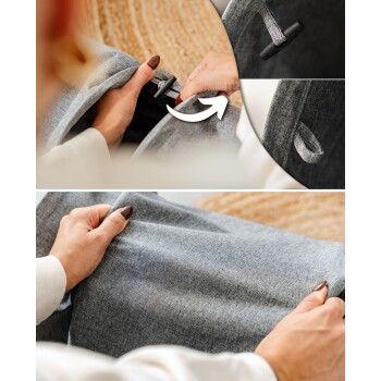 Eine Person mit manikürten Nägeln demonstriert, wie man ein graues Stoff-Haustierbett anpasst, und zeigt eine Nahaufnahme des Befestigungsmechanismus.