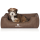Flauschiger braun-weißer Welpe sitzt in einem braunen Hundebett mit der Beschriftung KNUFFELWUFF und weißem Hundelogo.