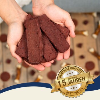 Hände halten einen Haufen brauner Haustier-Leckerlis, mit einem Abzeichen, das 'Bewährte Qualität seit über 15 Jahren - Best Quality' in der Ecke angibt.