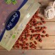 Eine Tüte "Pawtastic" Katzenleckerlis, die rote würfelförmige Stücke auf eine Holzoberfläche auskippt.