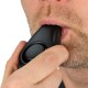 Een close-up van een man die een zwarte clicker voor huisdiertraining gebruikt, deze dicht bij zijn mond houdend, met een lichte baard en een gefocuste uitdrukking.