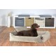 Ein glücklicher brauner Labrador Retriever sitzt bequem in einem plüschigen, hellgrauen Hundebett, mit einem modernen Wohnkultur-Hintergrund.