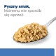 Łyżka miękkiej, beżowej karmy dla zwierząt z napisem "Pyszny smak, któremu nie sposób się oprzeć" nad nią.