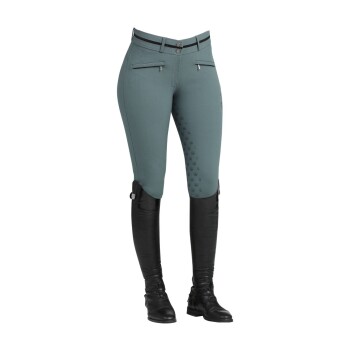Teal Damen-Reitleggings mit Reißverschlusstaschen, Silikon-Grip an den Innenseiten der Beine und hohen schwarzen Reitstiefeln.