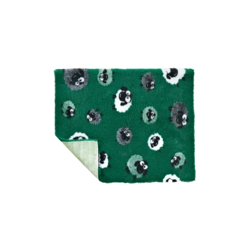Fuzzy green pet mat with black, white and gray sheep pattern, folded corner showing light-green striped backing