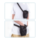 Eine Person in einem weißen T-Shirt und beigen Shorts verwendet eine schwarze Leckerlitasche für Haustiere, die entweder quer über den Körper oder an der Hüfte getragen wird.