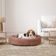 Ein gemütliches, rundes pinkes Hundebett mit einem Beagle, der bequem darauf liegt, in einem modernen Wohnzimmer mit einem hellen Teppich und Möbeln.