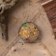 Eine Holzschüssel gefüllt mit buntem Vogelfutter, einschließlich Körnern, Mais und getrockneten Früchten, auf einer Juteschicht mit verstreuten Samen.