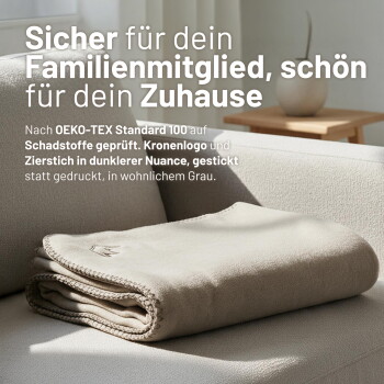 Gefaltete beige Hundedecke auf Sofa mit deutschem Text 'Sicher für dein Familienmitglied, schön für dein Zuhause' und Hinweis auf OEKO‑TEX.