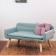 Ein stilvolles hellblaues Haustiersofa mit Holzbeinen, mit zwei rosa Kissen, vor einer schlichten Wand und einem Holzboden.