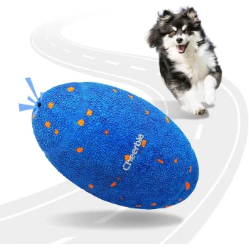 Blaues, strukturiertes Hundespielzeug in Form eines Footballs mit orangefarbenen Flecken und dem Schriftzug „Cheerble“, mit einem fröhlichen schwarz-weißen Hund, der dahinter läuft.