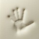 Ein Handabdruck, der in feinen, hellen Sand gedrückt wurde, zeigt die Details der Finger und der Handfläche vor einem glatten Hintergrund.