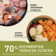 Rohe Haustierfutterzutaten in einer Schüssel: Huhn, Truthahn, Forelle, Apfel und Kürbis. Text bemerkt "70% hochwertige tierische Zutaten."