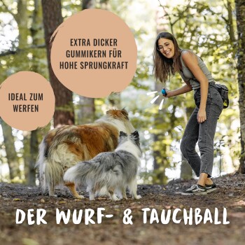 Eine Frau in lässiger Kleidung hält ein buntes Hundespielzeug in einem Wald, während zwei Hunde zu ihr aufblicken. Text lautet "DER WURF- & TAUCHBALL."