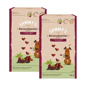 Deux paquets de friandises pour chiens 'Sammy's Herzensbrecher', avec un chien de dessin animé entouré de cœurs, étiqueté avec les ingrédients : 'mit Rote Beete & Lockenstücken.'