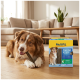 Brauner Hund liegt auf Holzboden neben einer gelben MultiFit Dental Care Sticks-Box in einem Wohnzimmer.