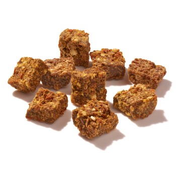 Ein Haufen knuspriger, rechteckiger Haustierleckerlis in verschiedenen Brauntönen, verstreut auf einem weißen Hintergrund.