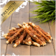 Ein Haufen hochwertiger Haustierleckereien aus verdrehtem Fleisch, das um Rohhide-Sticks gewickelt ist, auf einer Holzoberfläche mit grünem Gras im Hintergrund.