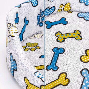 Bunte Haustierbett mit einem verspielten Design, das blaue und gelbe, gepunktete Knochen und Pfotenabdrücke auf einem weißen Hintergrund zeigt.