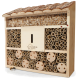 Holzinsektenhotel mit einem schrägen Dach, mit verschiedenen hohlen Röhren und Fächern für Bienen und nützliche Insekten, mit einer Biene auf dem Boden.