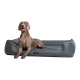 Ein grauer Hund liegt auf einem plüschigen Hundebett mit einem dunkelgrauen Stoff. Text auf dem Bild lautet "INKLUSIVE" und "MATRATZENSCHONER GIBT'S OBENDRAUF."