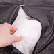 Eine Hand hält einen weißen Stoff in einem teilweise geöffneten schwarzen Haustierbettbezug und zeigt das Füllmaterial.