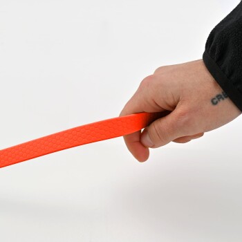 Eine Hand hält eine leuchtend orangefarbene, strukturierte Hundeleine vor einem weißen Hintergrund.