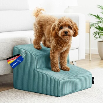 Kleiner brauner, lockiger Hund auf petrolfarbenen, gerippten zweistufigen Haustierstufen neben weißem Sofa; Etikett lautet 'DEUTSCHE MARK' und 'MADE IN EU'.