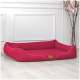 Ein stilvolles rotes Haustierbett mit weißer Paspelierung und einem "tier ando"-Tag, auf einem hellen Holzboden vor einer weißen Wand platziert.
