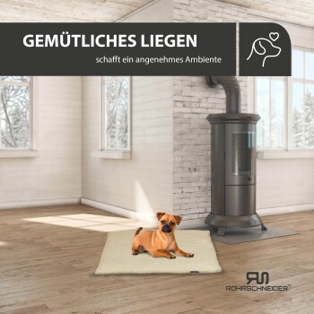 Ein gemütlicher Hund auf einem beigen Bett in einem hellen Raum mit einem Holzofen und großen Fenstern, mit dem Text: "GEMÜTLICHES LIEGEN schafft Ambiente."