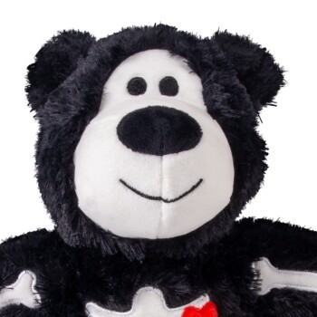 Plush black-and-white stuffed animal with round black nose, stitched smile and white bone-shaped patches on its chest