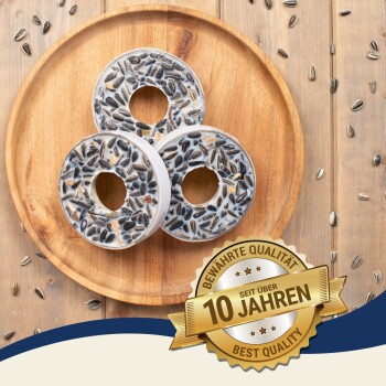 Drei runde Vogelhäuschen, gefüllt mit Sonnenblumenkernen auf einem Holzbrett, begleitet von einem 'Beste Qualität'-Abzeichen mit der Aufschrift '10 Jahre'.