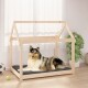 Ein Collie, der auf einem gemütlichen grauen Bett in einem Holzhaustierhaus entspannt, mit einem hellen Raum und Pflanzen im Hintergrund.