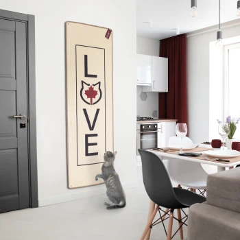 Eine graue Katze steht auf ihren Hinterbeinen und greift nach einem Wandbehang, der "LOVE" mit einer Katzensilhouette und einem Ahornblatt-Design sagt.