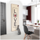 Eine graue Katze steht auf ihren Hinterbeinen und greift nach einem Wandbehang, der "LOVE" mit einer Katzensilhouette und einem Ahornblatt-Design sagt.