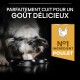 Un chien merle renifle deux bols noirs étiquetés "PURINA PRO PLAN" avec le texte : "PARFAITEMENT CUIT" et "N°1 INGREDIENT POULET."