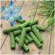 Grüne zylindrische gefriergetrocknete Tierleckerlis auf Holzbrett mit Gras und blauem Schneeflocken-Schriftzug 'Gefrier-getrocknet'